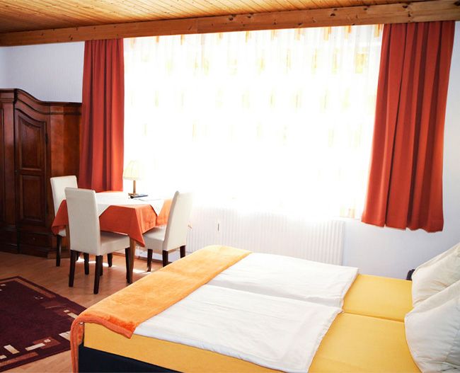 Blick auf einen großen Raum mit Schrank, Doppelbett, Tisch und Stühlen